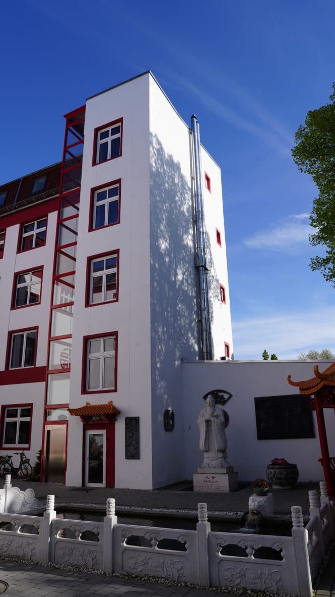 Steinfigur neben der Treppe mit weißer Balustrade und rotem Eingang